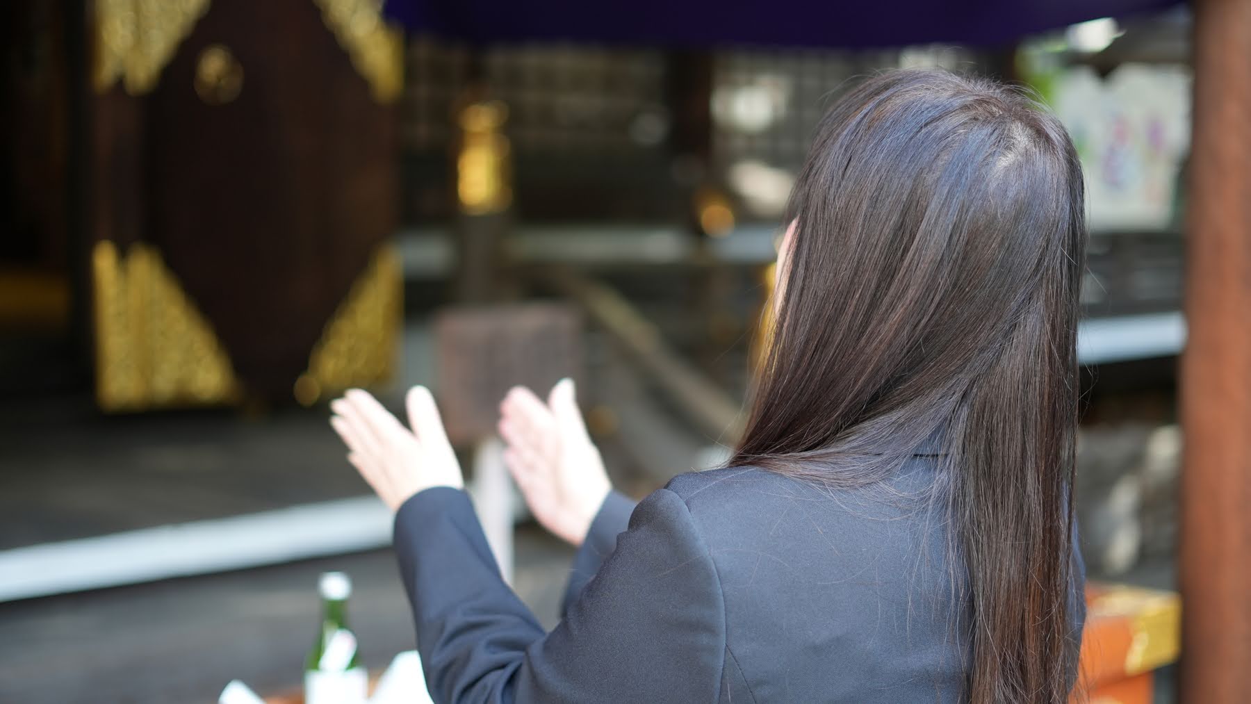 本殿の前で一人静かに祈る女性の後ろ姿